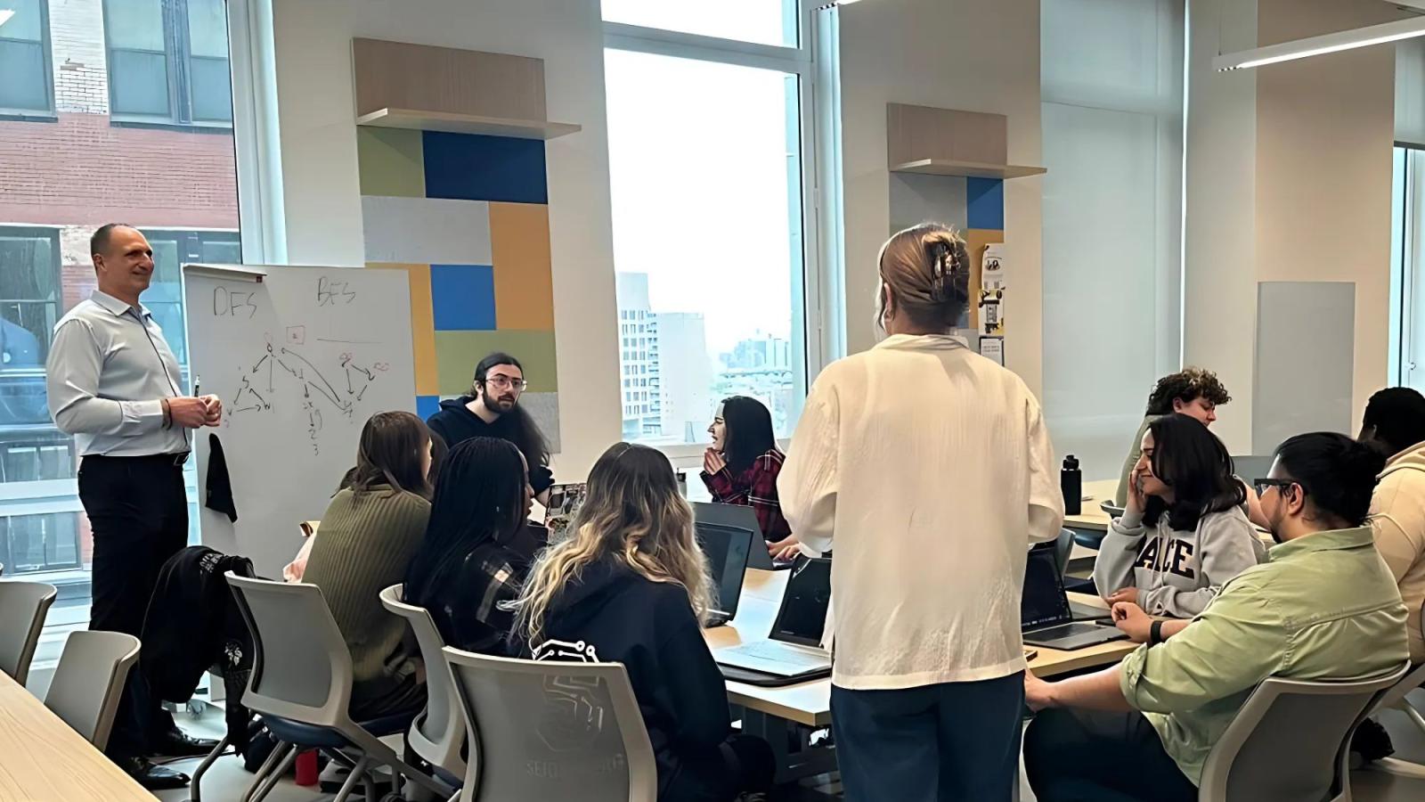 Pace Seidenberg professor Joe Acampora working with a group of students who are sitting around a table in Seidenberg's Design Factory space.