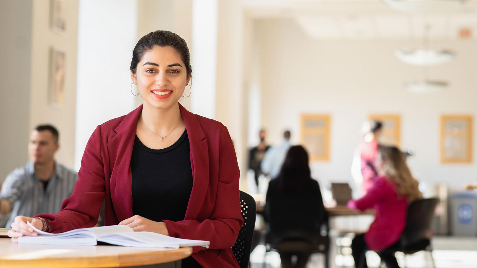 Student sitting at a desk, smiling at the camera.