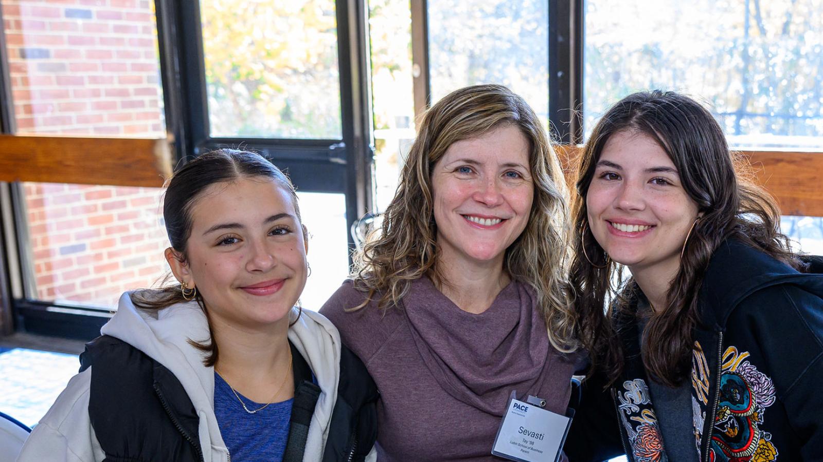 Parent smiling at the camera hugging her Pace University students.