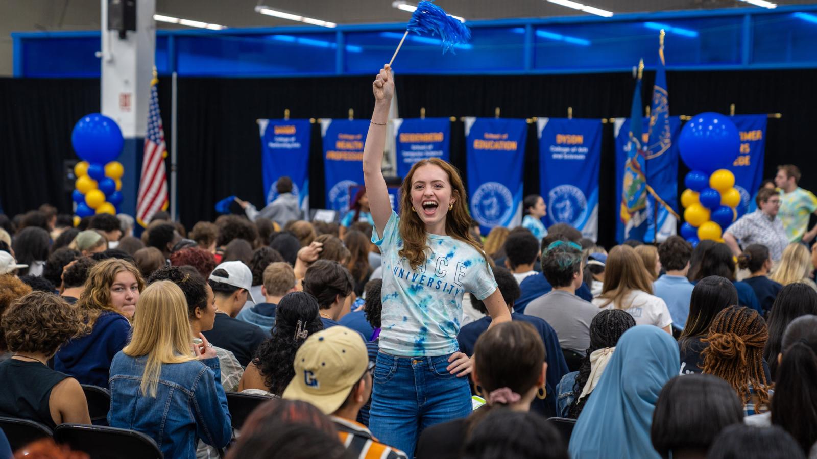 A student waving a pompom in the crowd at NYC Convocation.