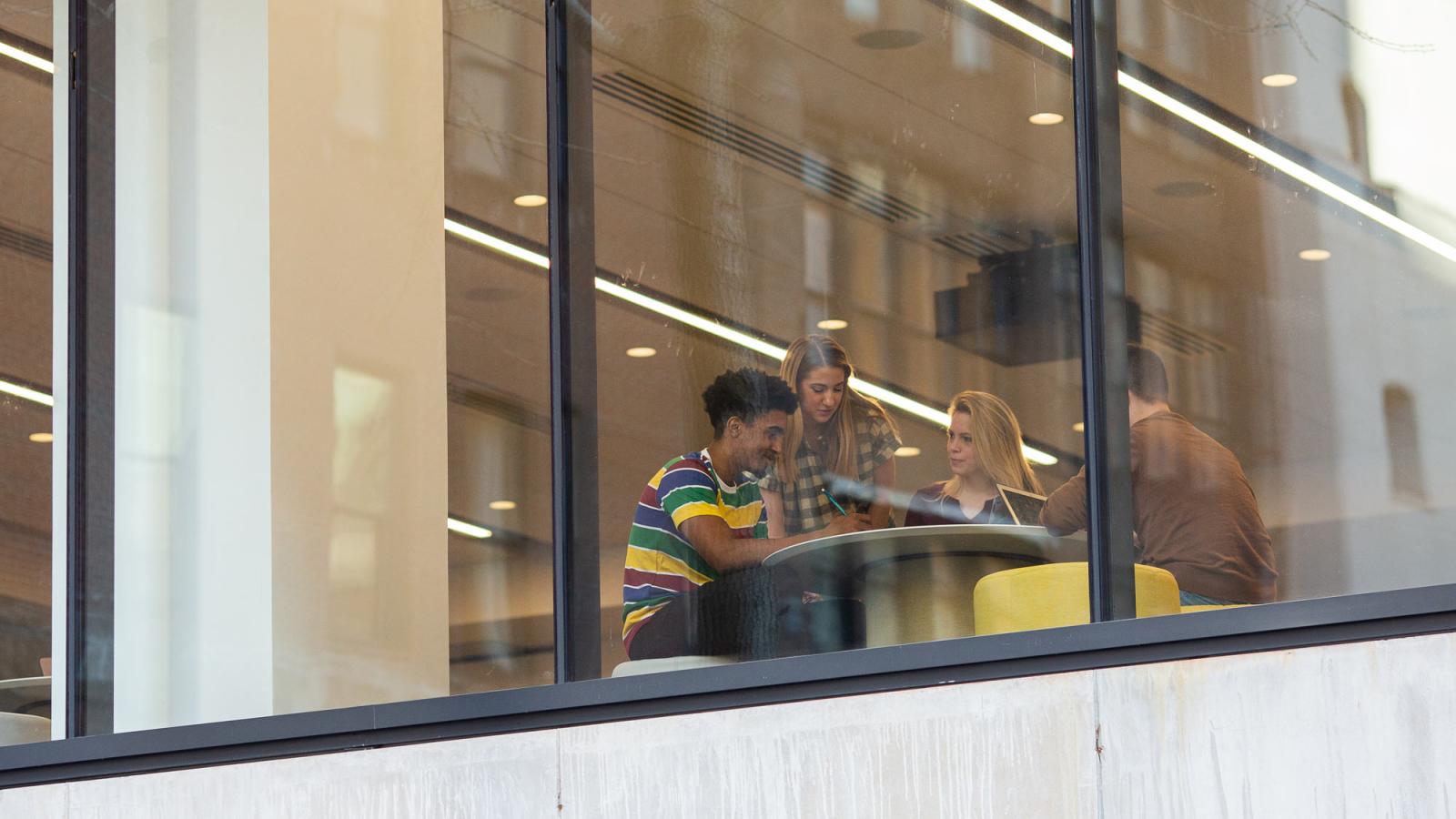 Students inside the Student Center at Pace University as seen through a window.