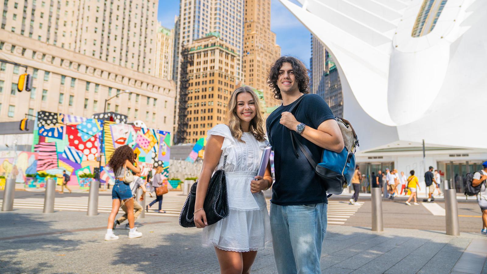 Two Pace University students stand outside in front of street art and the Occulus