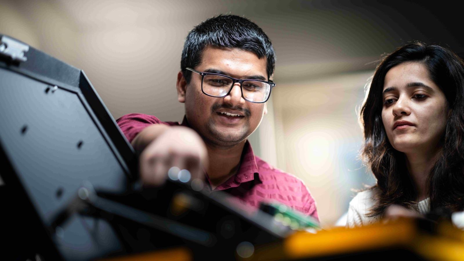 Two Seidenberg students working on a robot.
