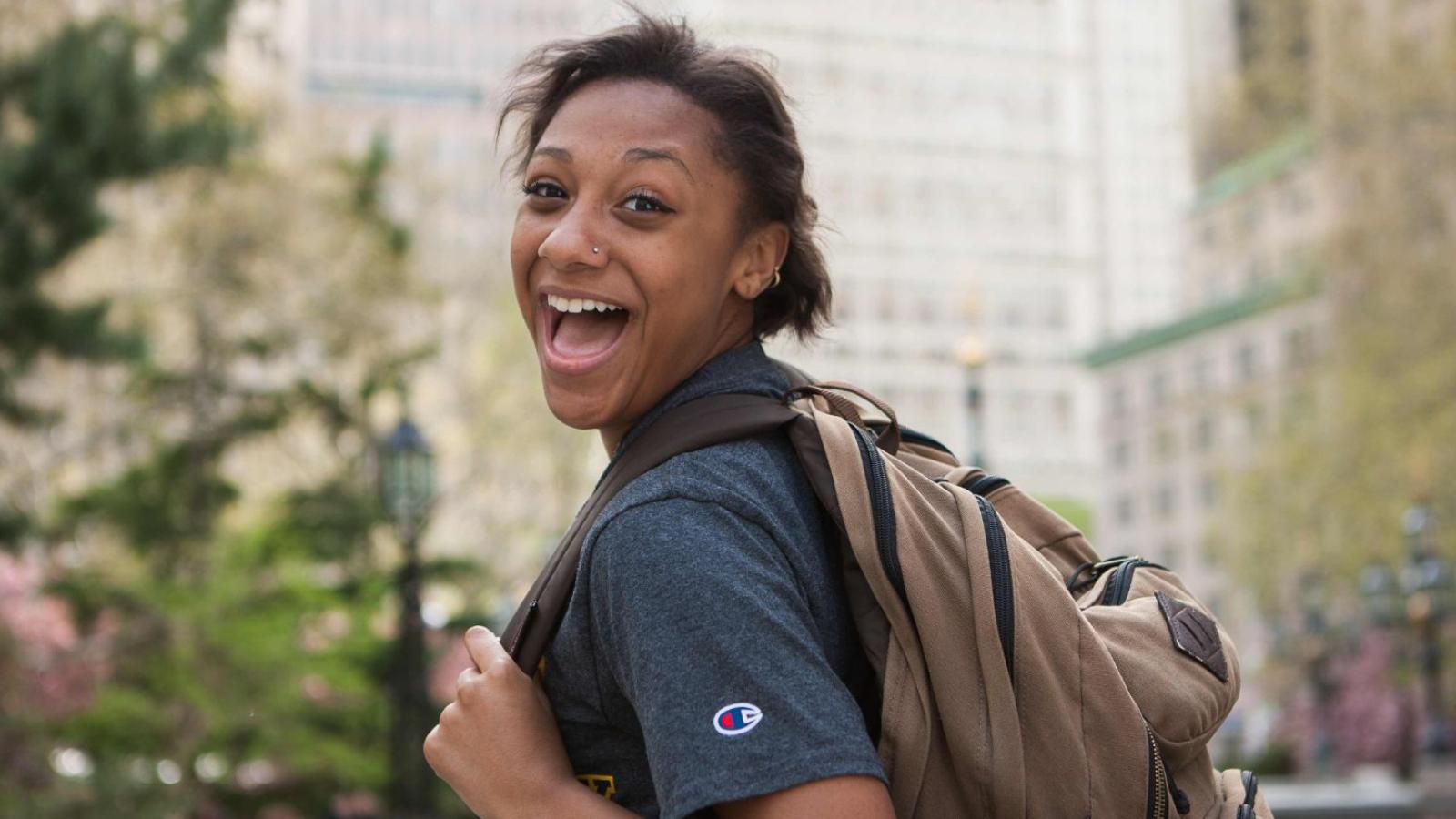 Pace student carrying a backpack and smiling while walking.