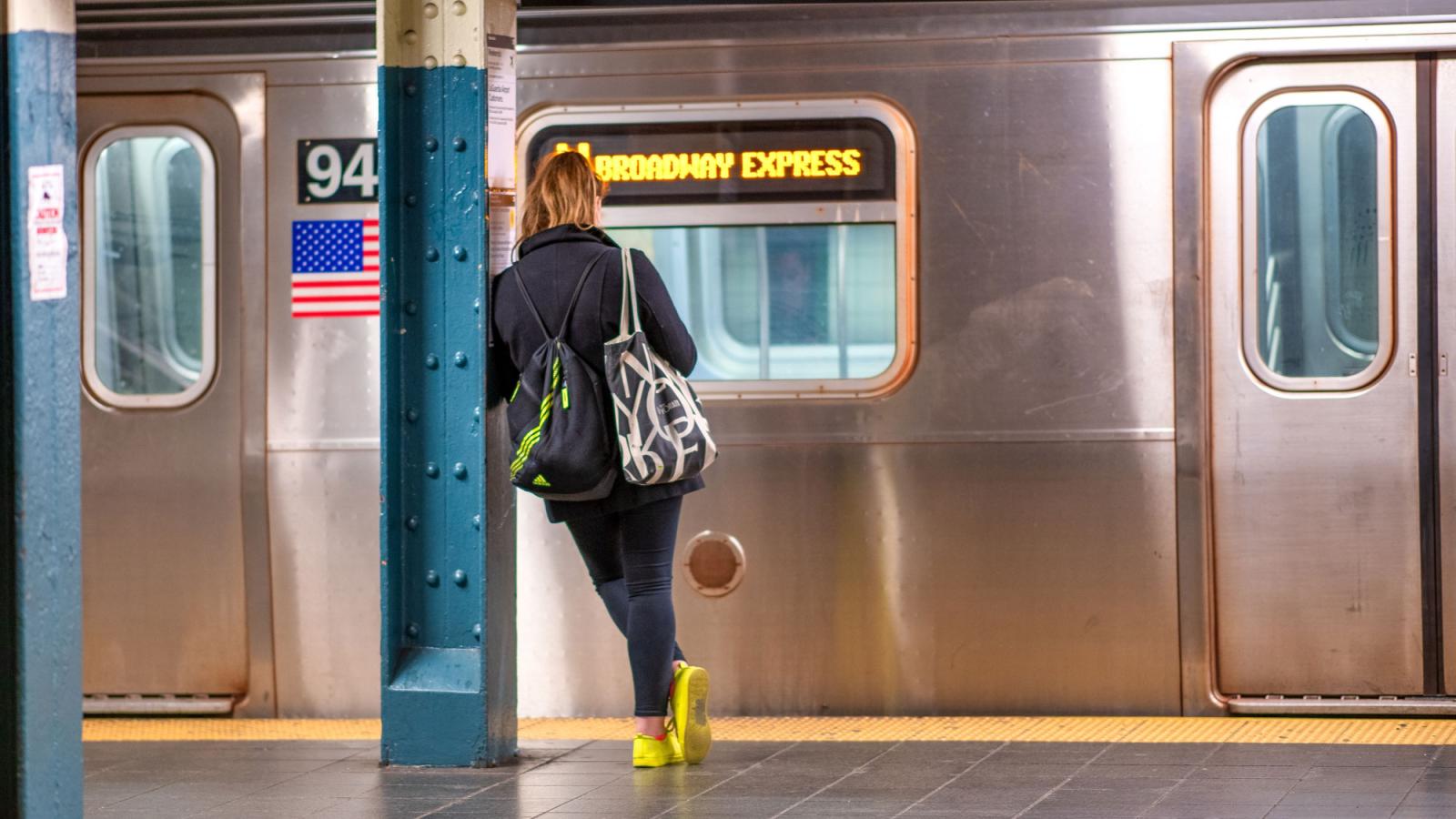 Woman standing on an NYC subway platform.