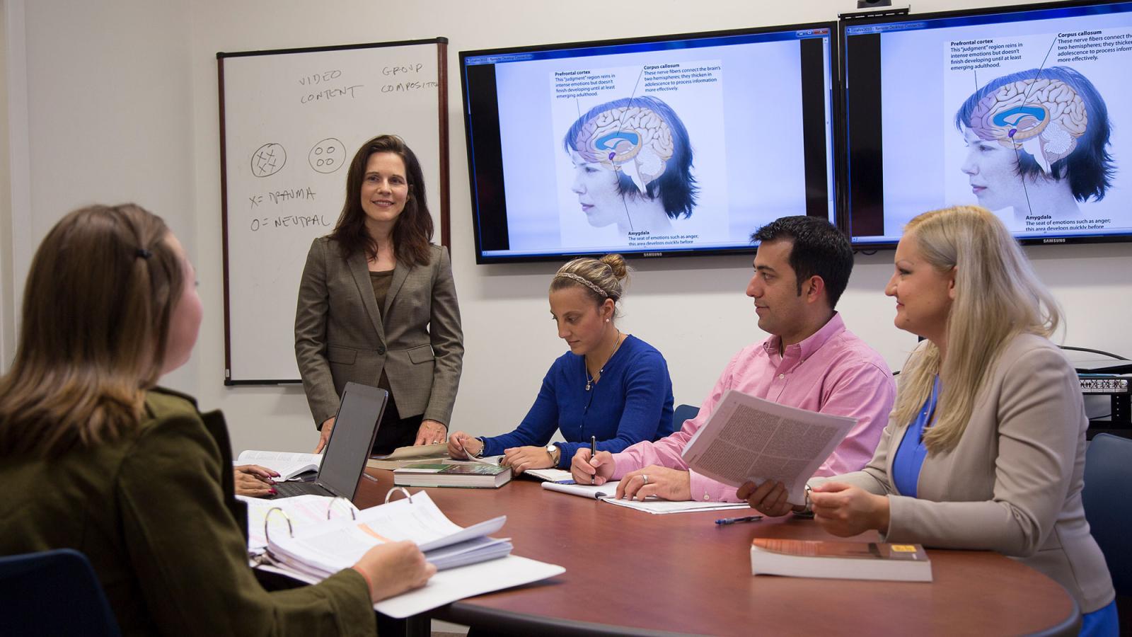 Group of graduate Pace University students sitting in a classroom, listening a their psychology Professor.