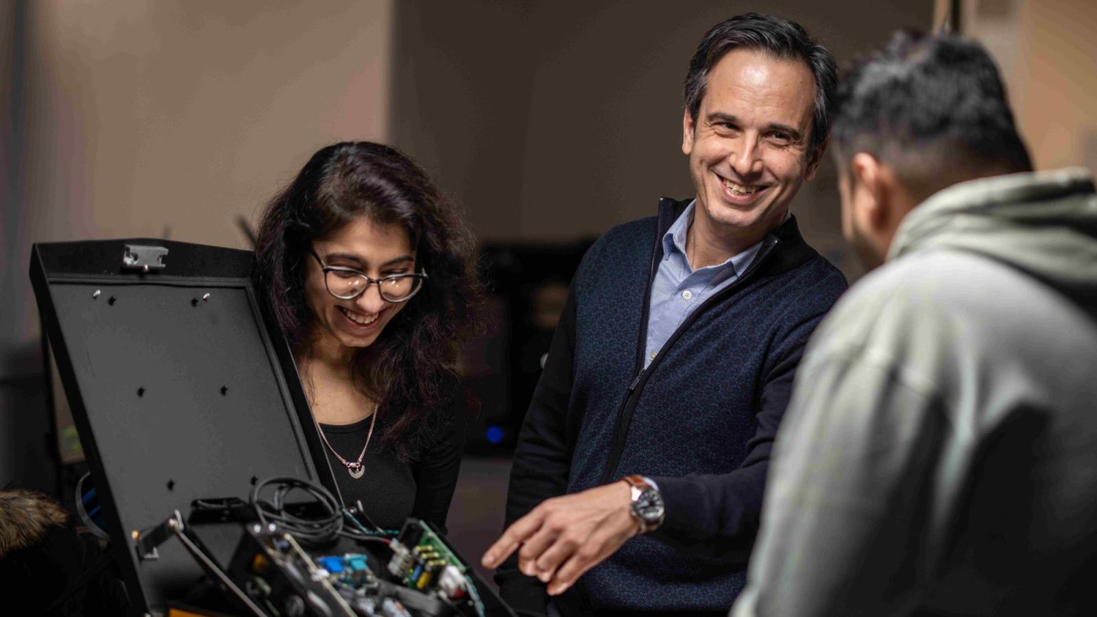 Seidenberg professor Dr. Yegin Genc working on a lab project with two students.