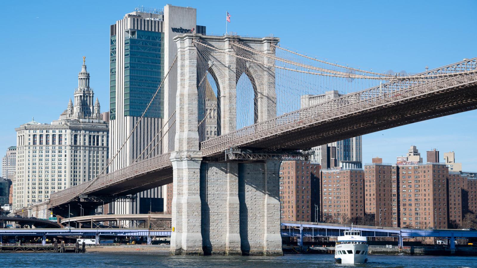 Iconic view of the Brooklyn Bridge spanning the East River, connecting Manhattan and Brooklyn with the New York City skyline in the background
