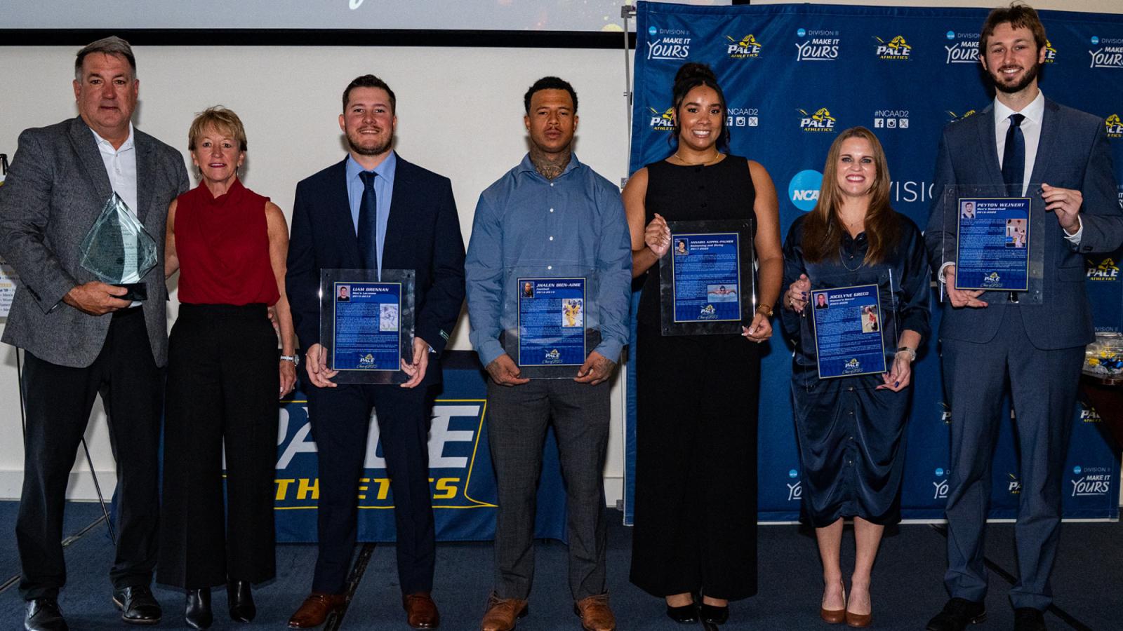 Pace University student-athlete alumni hold their awards from the 2025 Hall of Fame ceremony