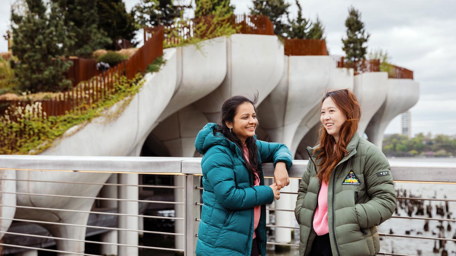 Two Pace students in winter coats standing in front of Little Islands Park.