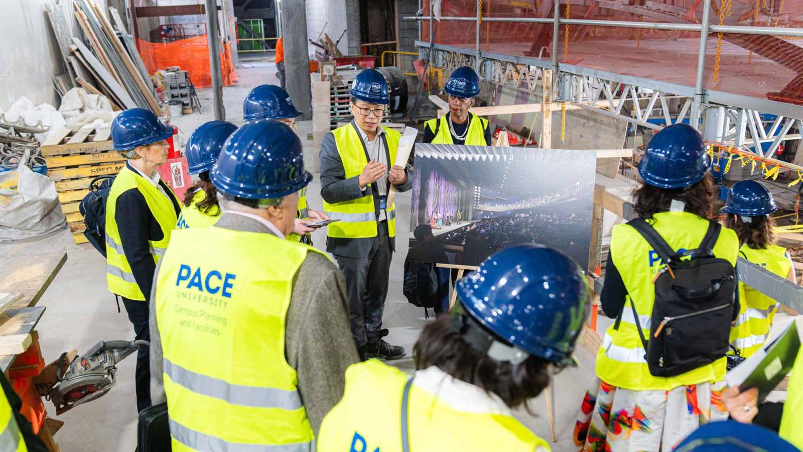 People in hardhats and construction vests looking at renderings within the construction site.