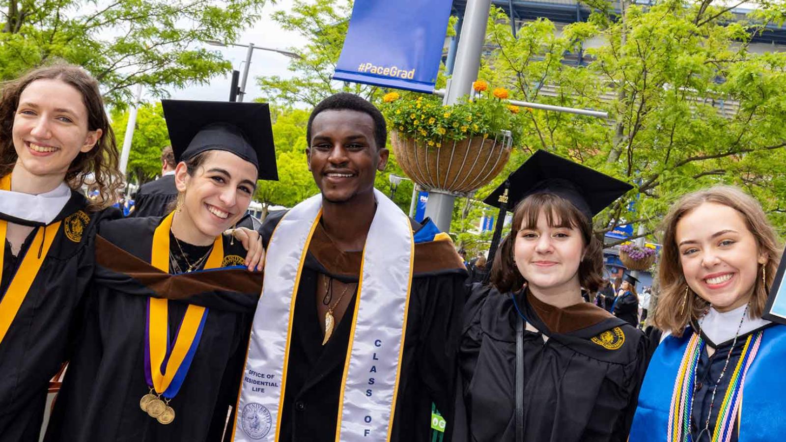 Group of student celebrating their Commencement ceremony, smiling at the camera.
