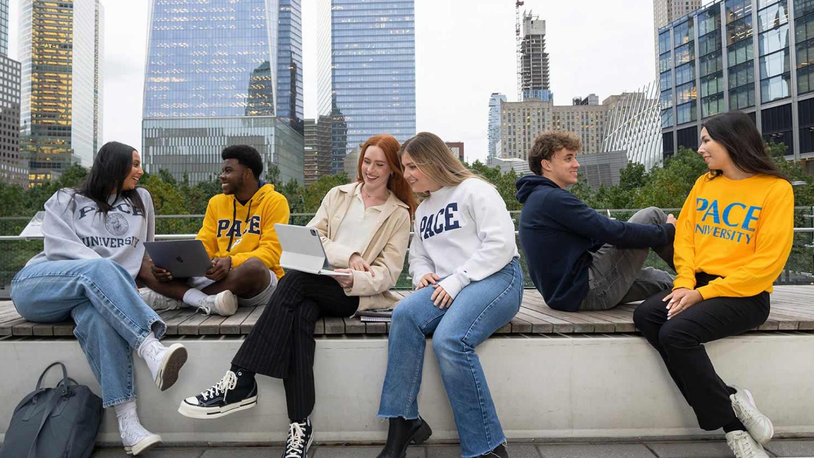 Group of Pace University students sitting on a wall in Manhattan and hanging out.