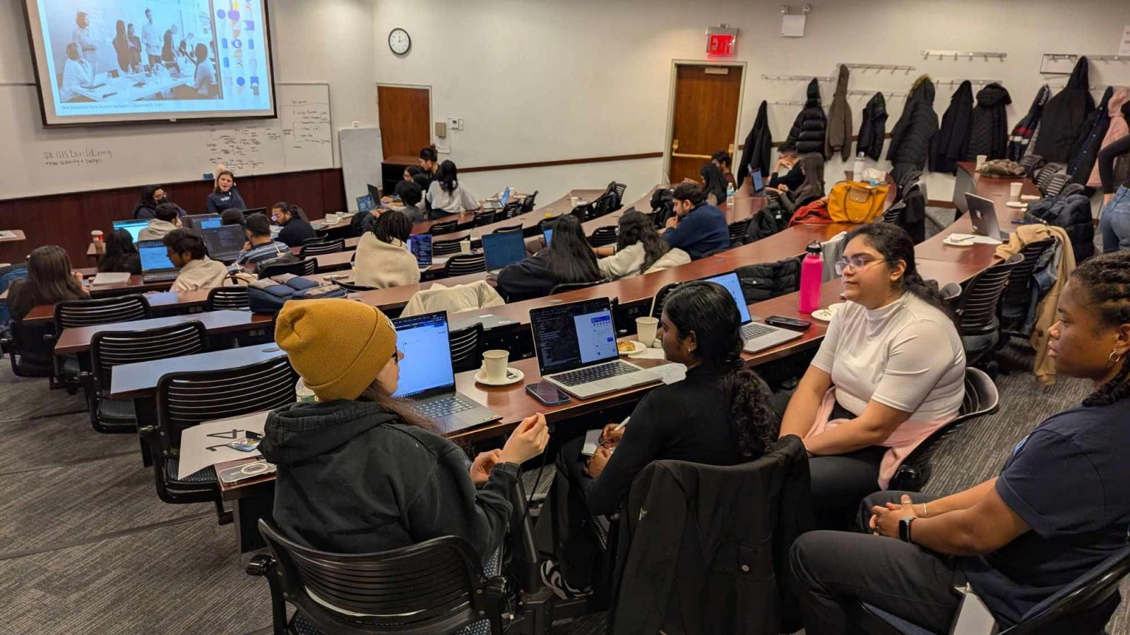 Pace Seidenberg students sitting in a lecture hall and working on their laptops during a hackathon.