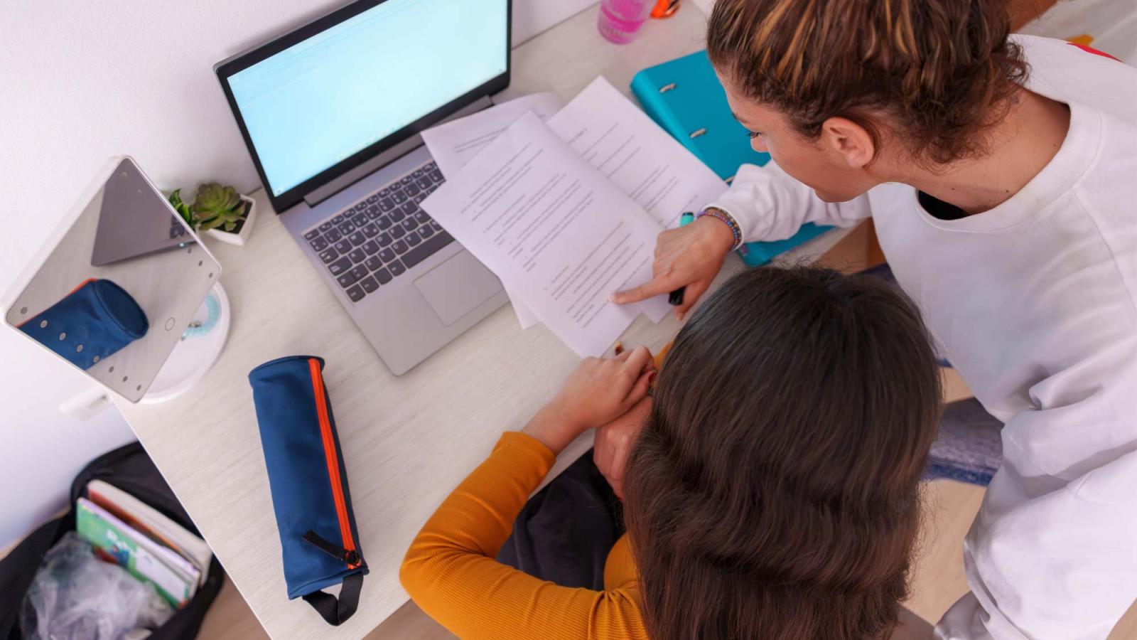 A parent and student reviewing documents at a computer.