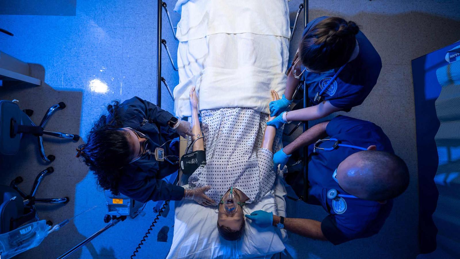Students working on a mannequin in the simulation lab.