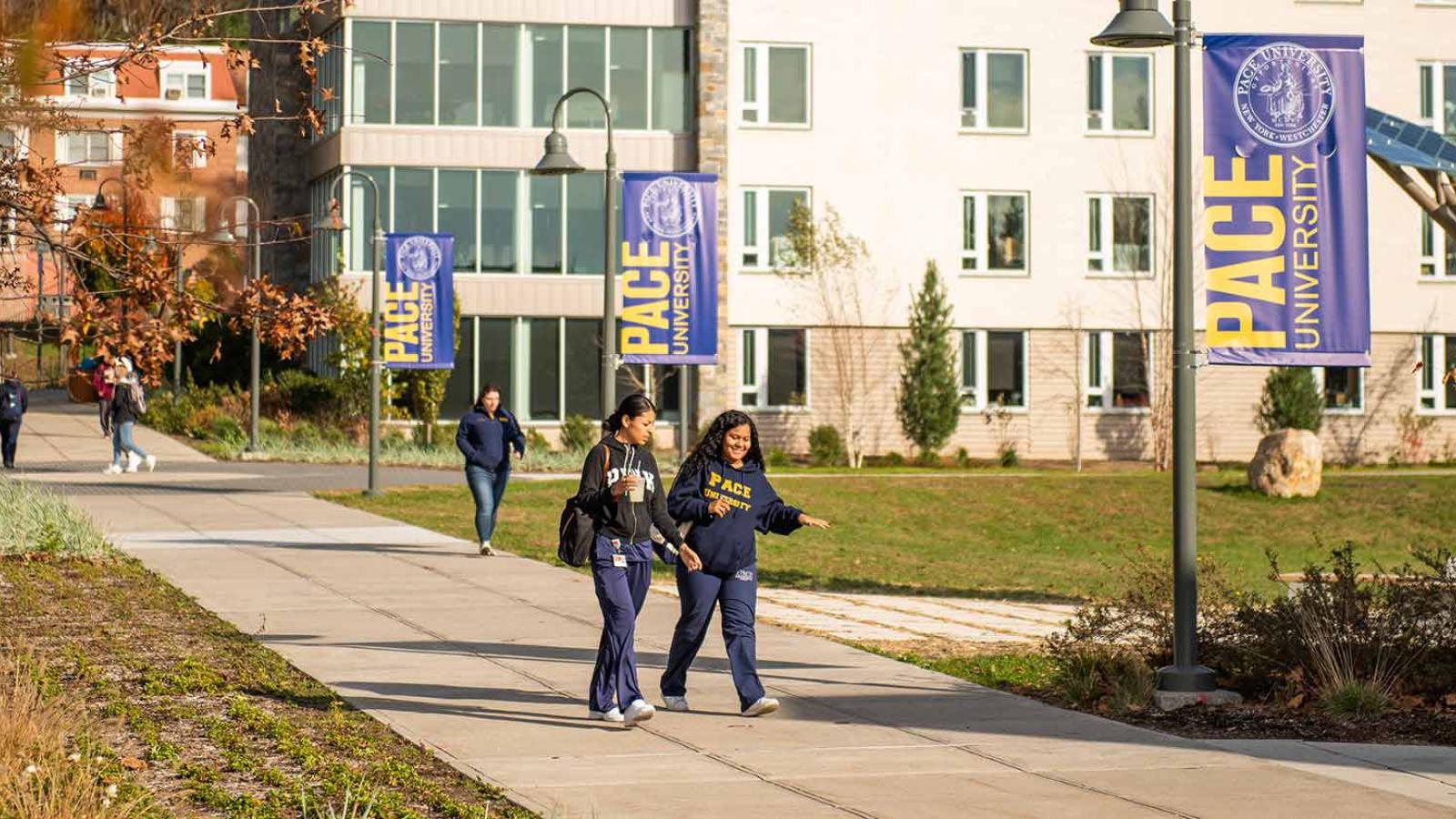 Students walking along a concrete path on the Pace University campus in Pleasantville, New York.