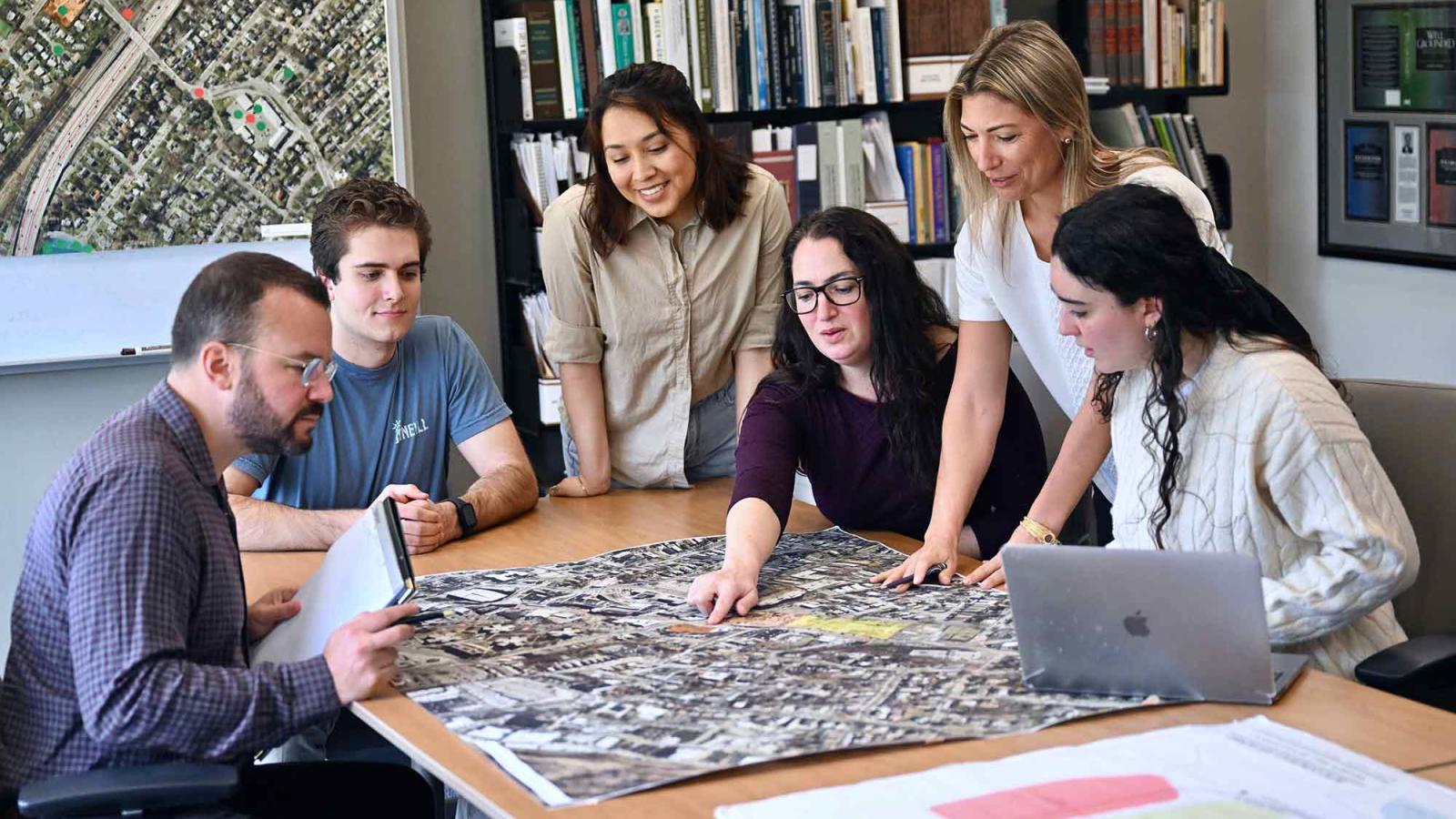 Students gathering around a table looking at a map