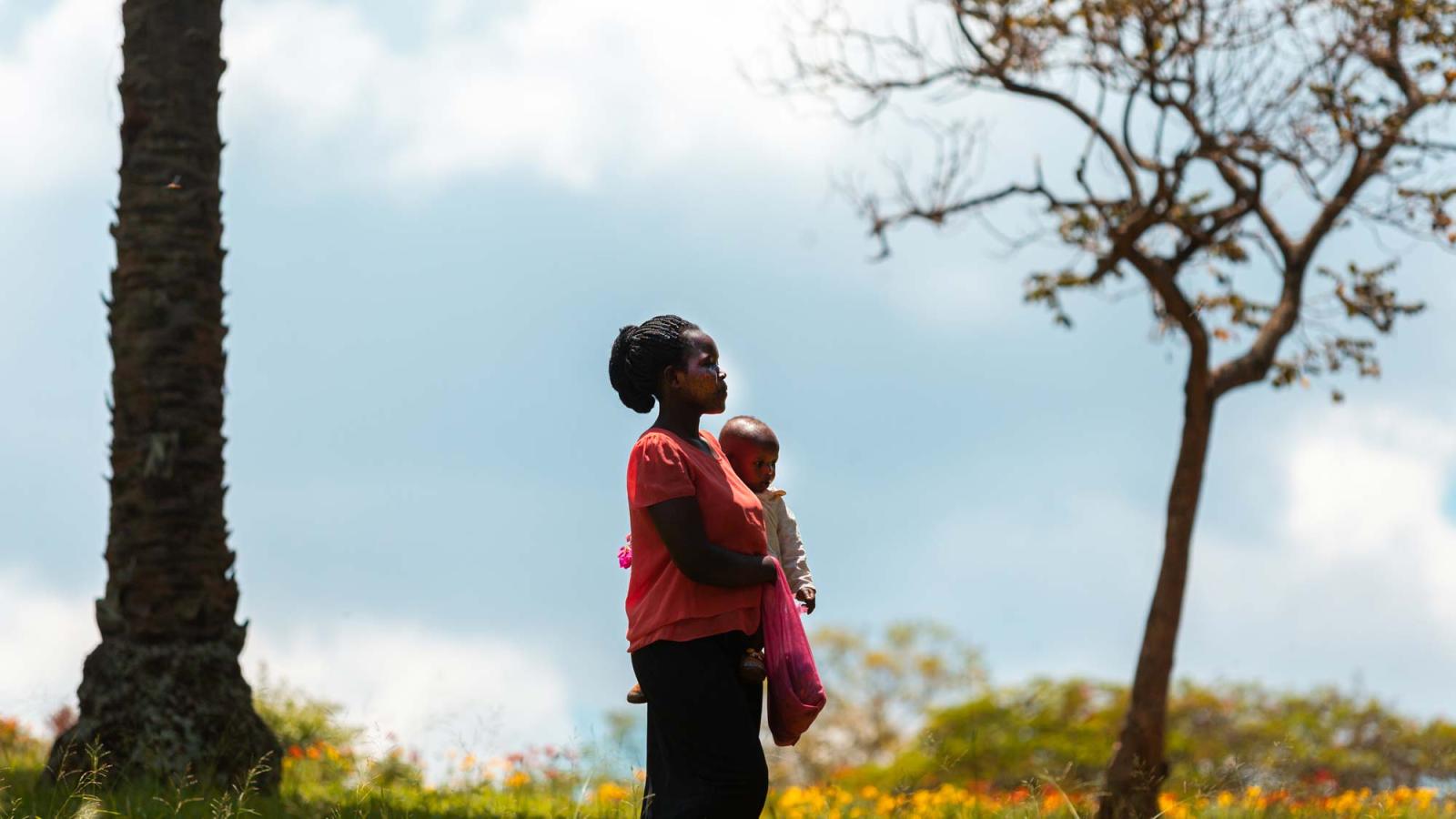 Young African mom walking in the garden of Baha'i House of Worship, with her baby. Kikaya district of Kampala, Uganda.