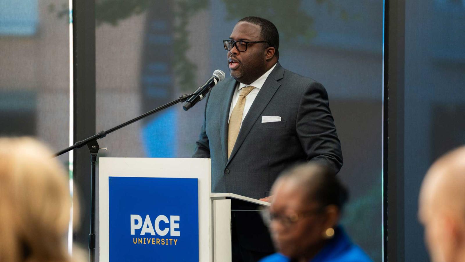Vincent Clark at a podium speaking into a microphone.