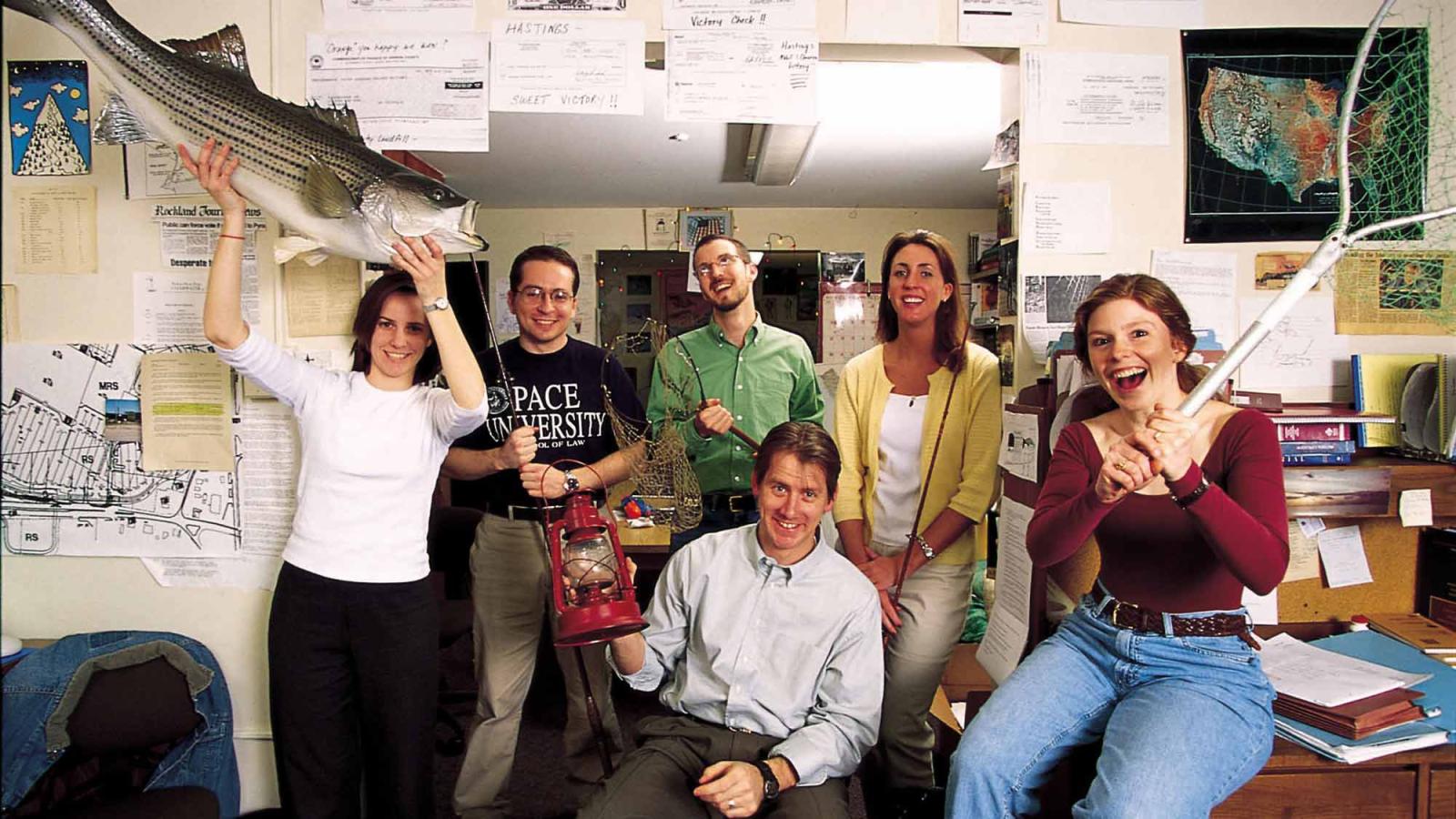 Group of Pace Haub Law students smiling at the camera, holding fishing equipment.