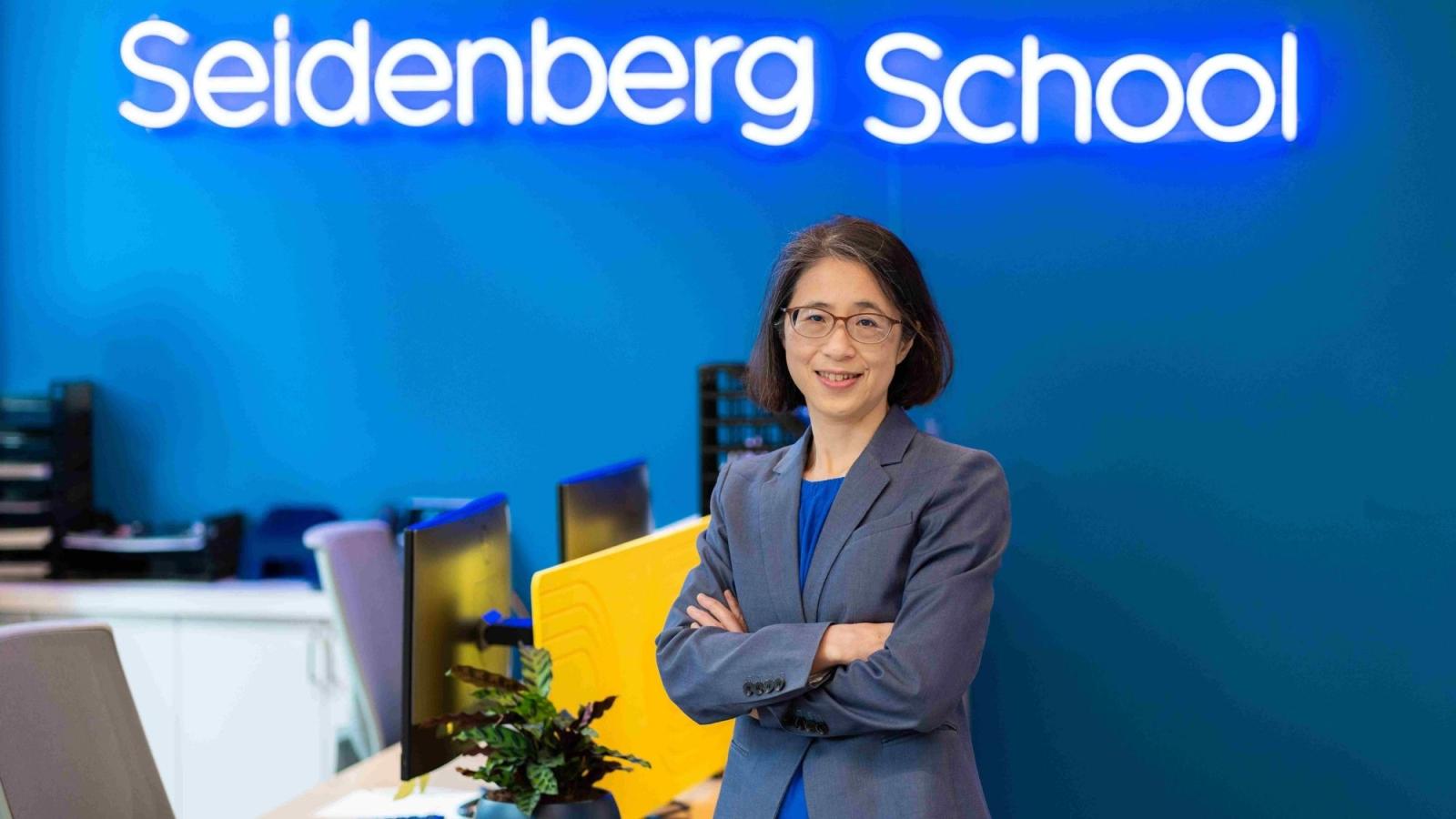 Seidenberg Dean Li-Chiou Chen in front of the school's neon sign