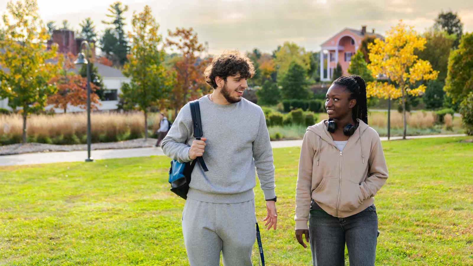 Two Pace students walking on the quad with Choate House in the distance.