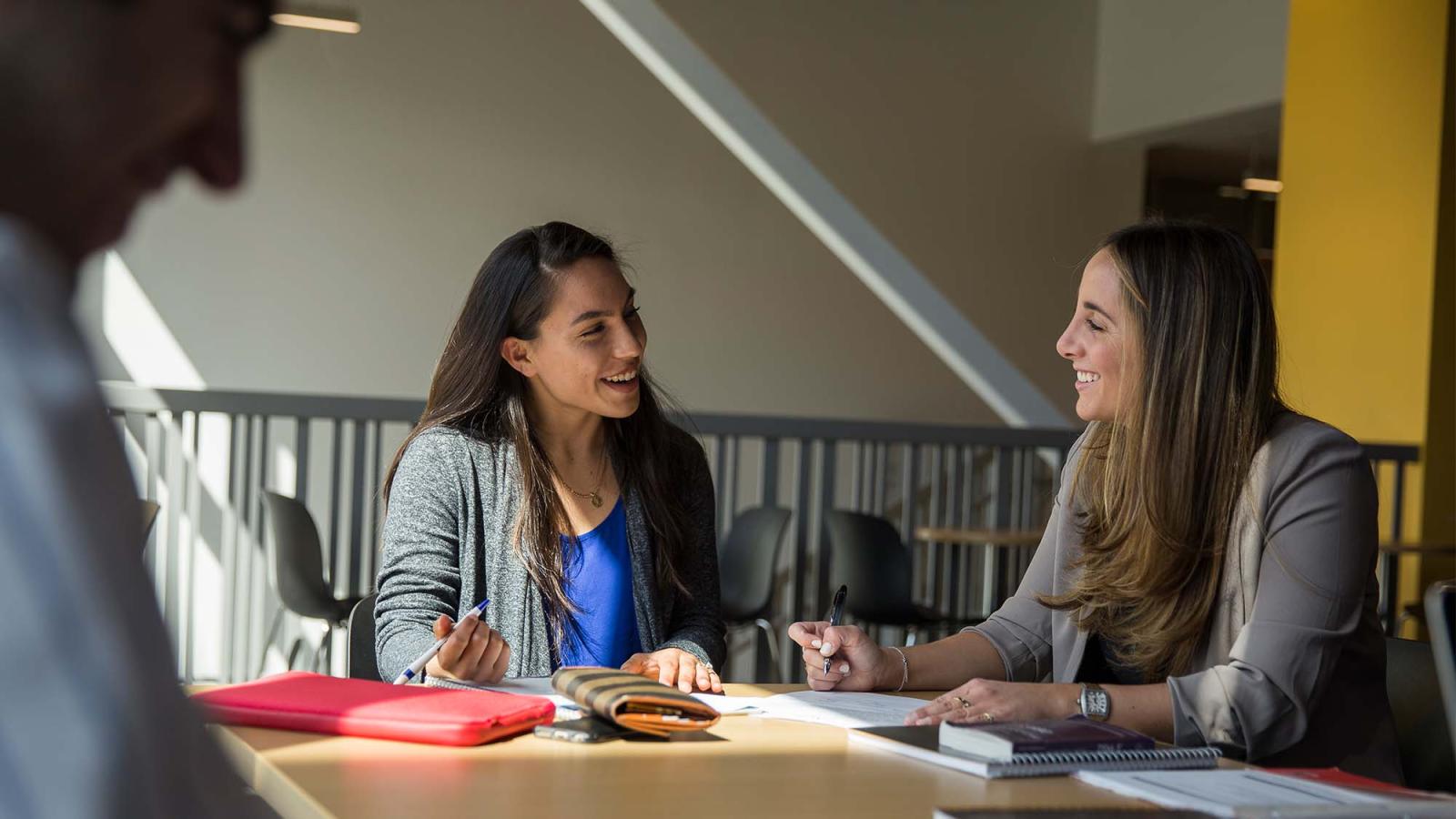 Two women sit at a table, studying