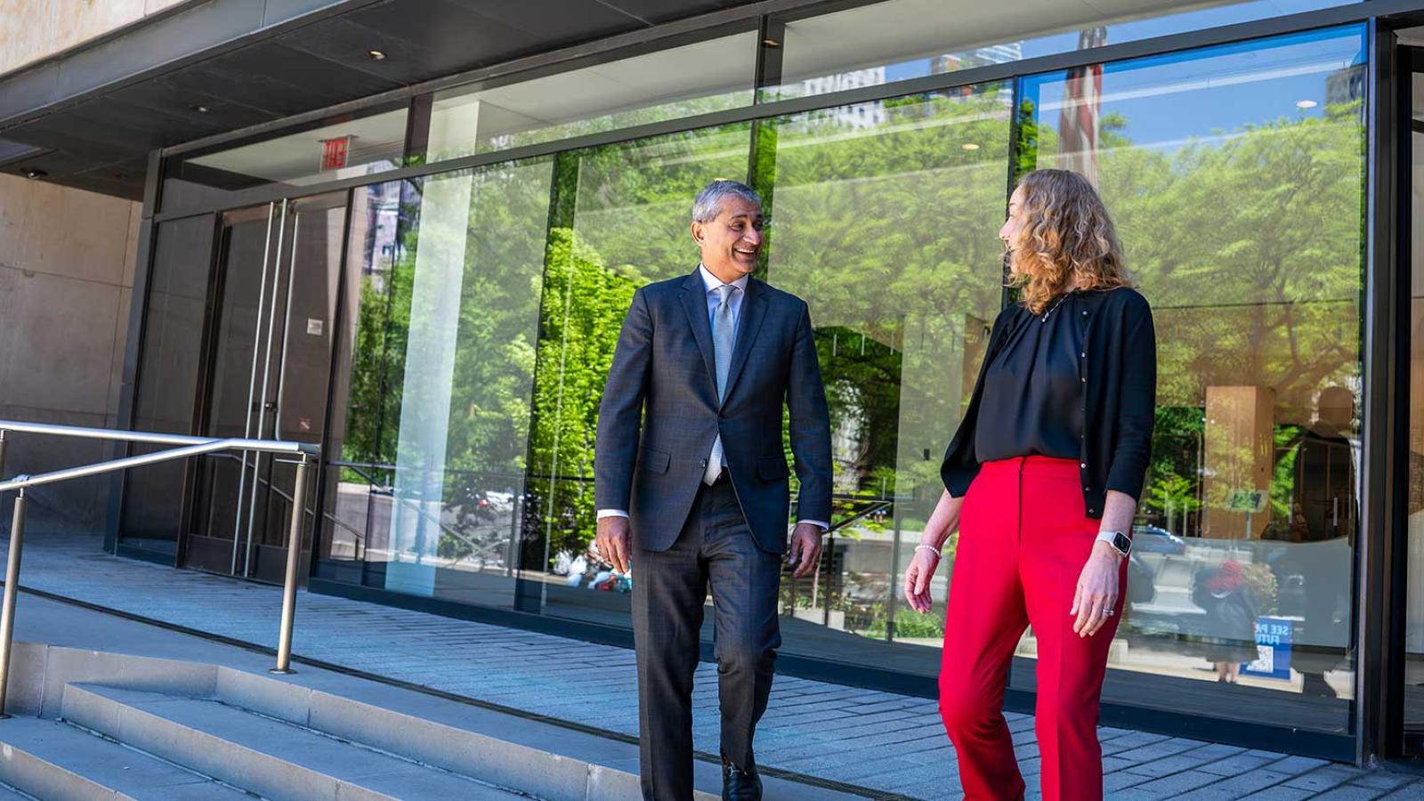 Lubin School of Business dean and faculty member walking down entrance steps, talking