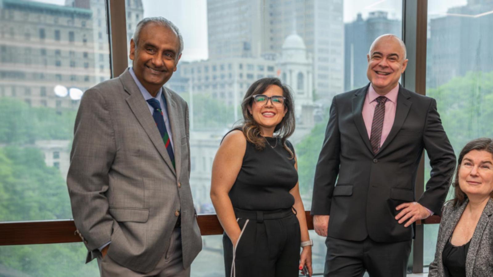 Four Pace University Lubin School of Business professors standing in front of window