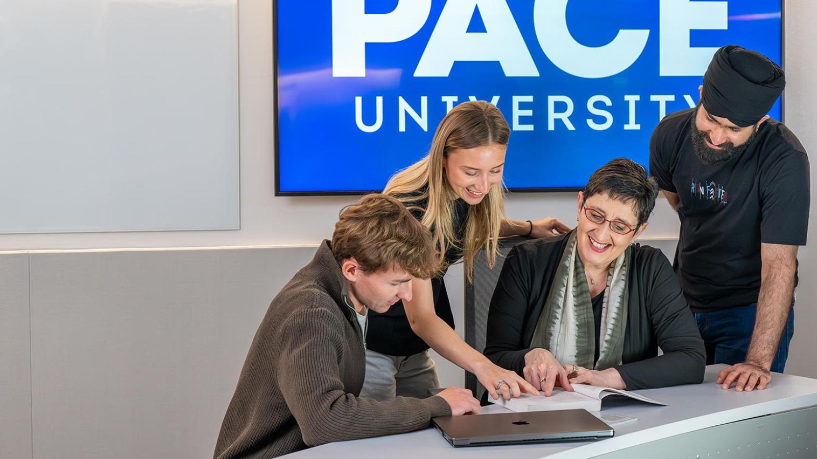 Pace University Lubin School of Business students and faculty member looking at a management book together