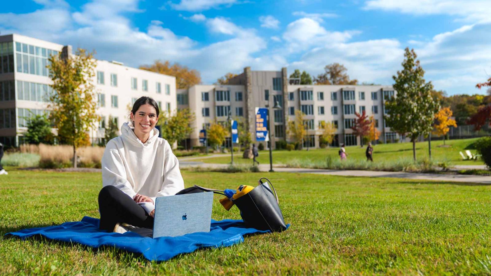 Pace University graduate student sitting on a blanket in the courtyard at Pace University's Westchester campus.
