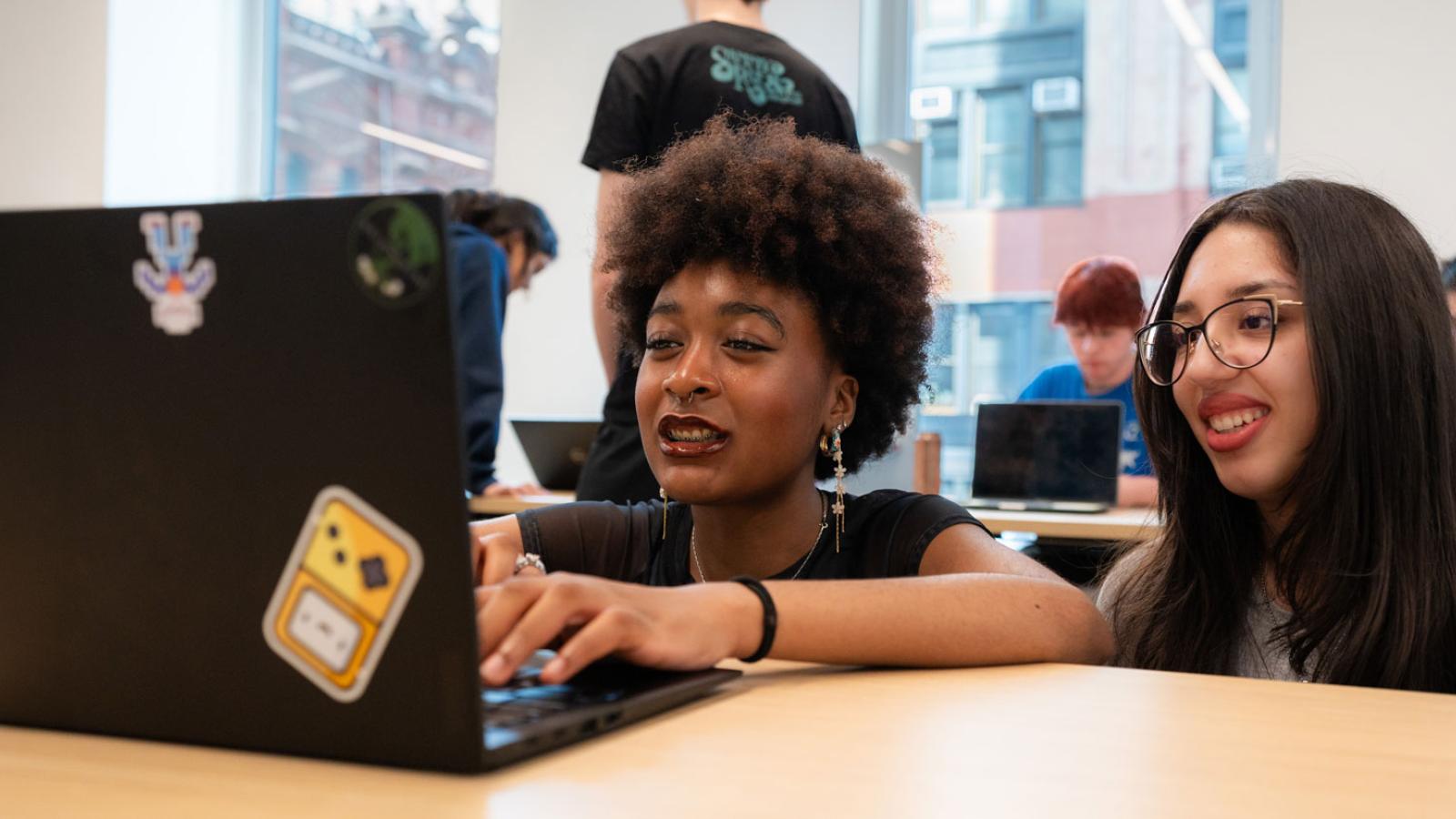 Two Pace University students working on a laptop.