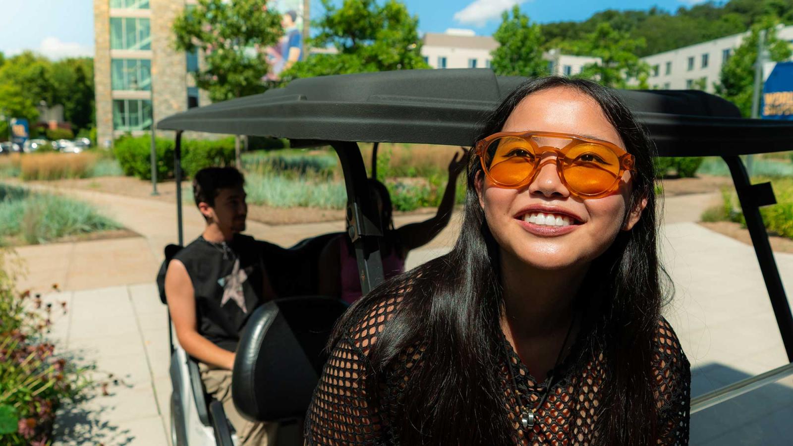 Pace University student sitting in a golf cart, smiling at the camera on the Westchester Campus.