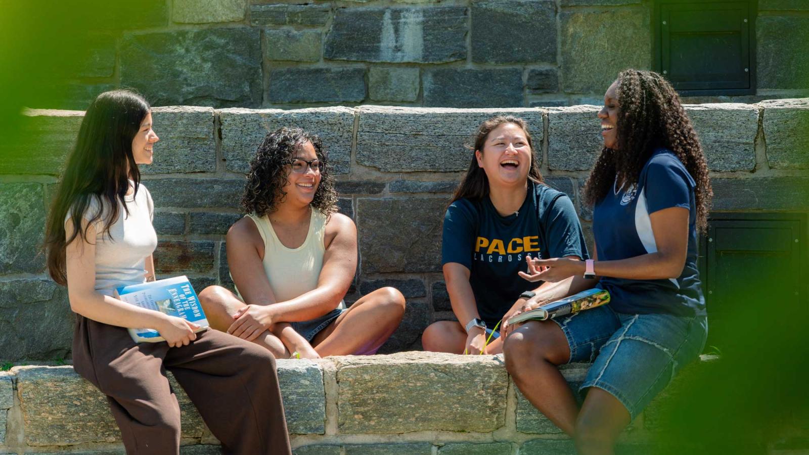 Groups of Pace University students on the Westchester campus sitting in the courtyard laughing. 
