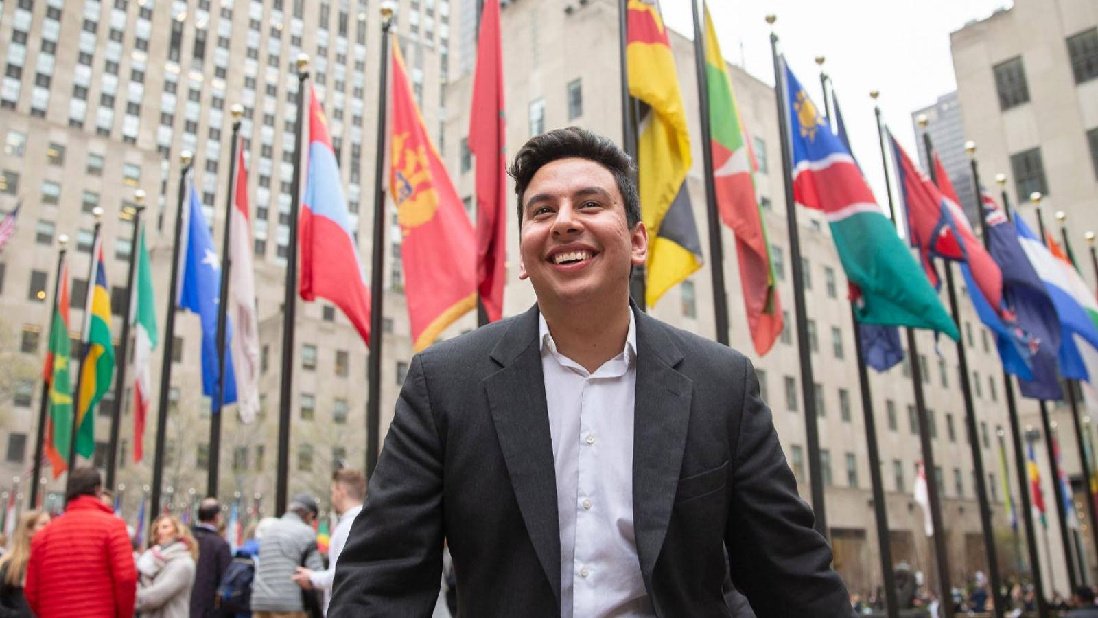 Young man standing in front of a row of world flags in New York City