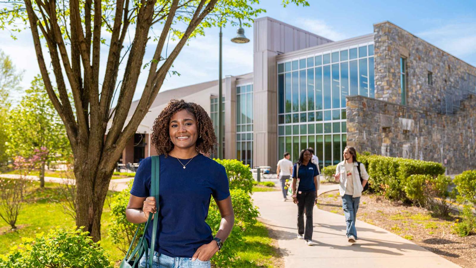 Pace University student standing outside of building, holding bag