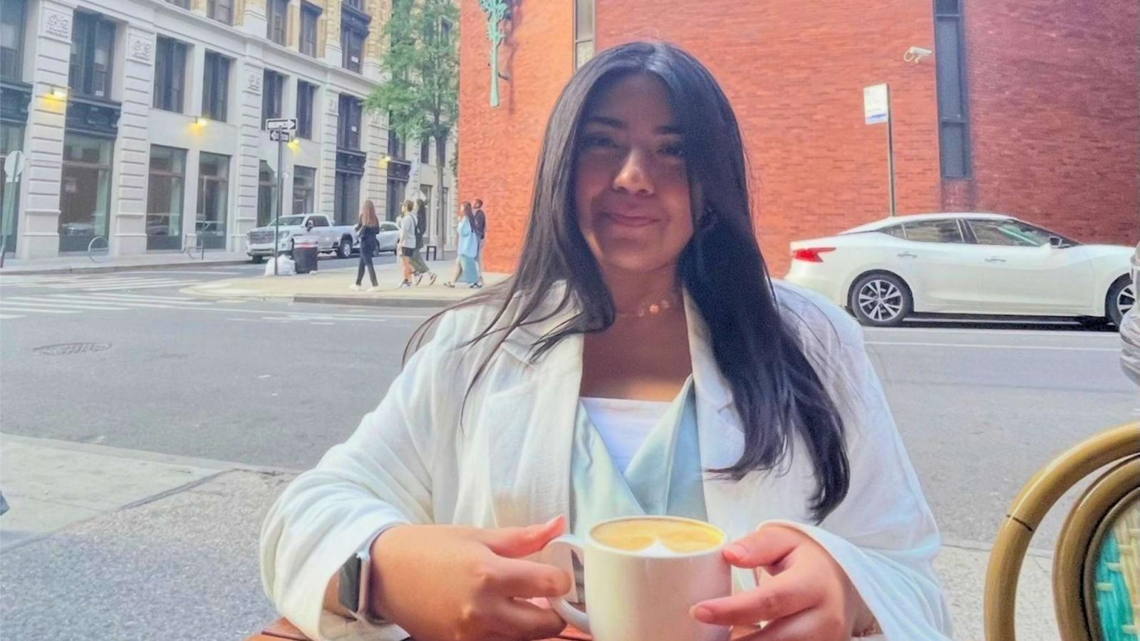 Seidenberg alum Laraib Sarmad sitting with a cup of coffee at a cafe in NYC