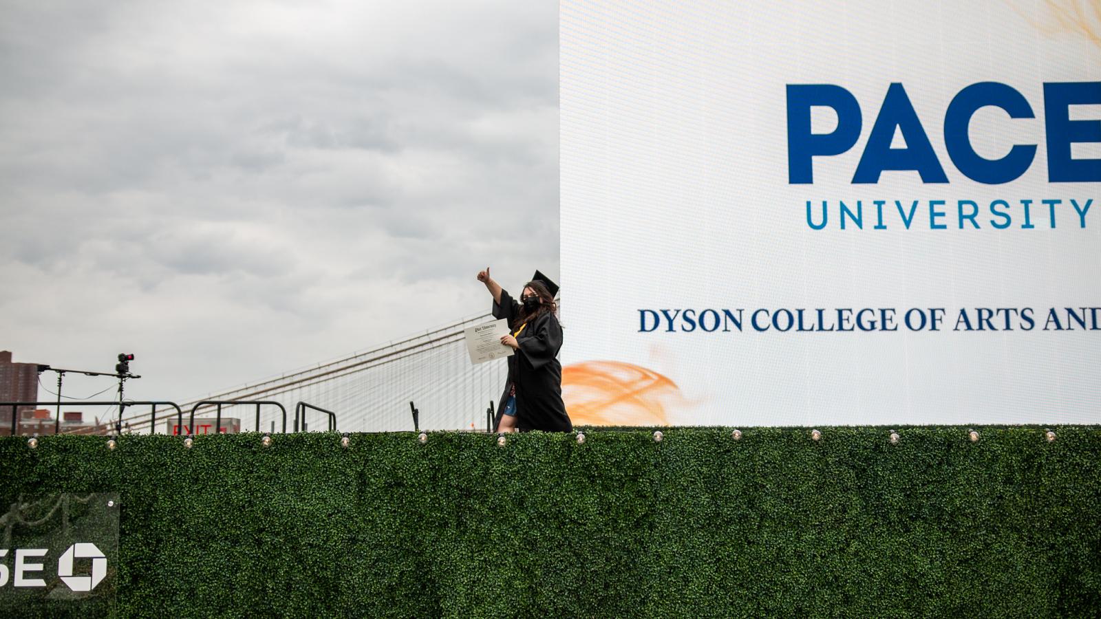 student in academic regalia crossing a stage