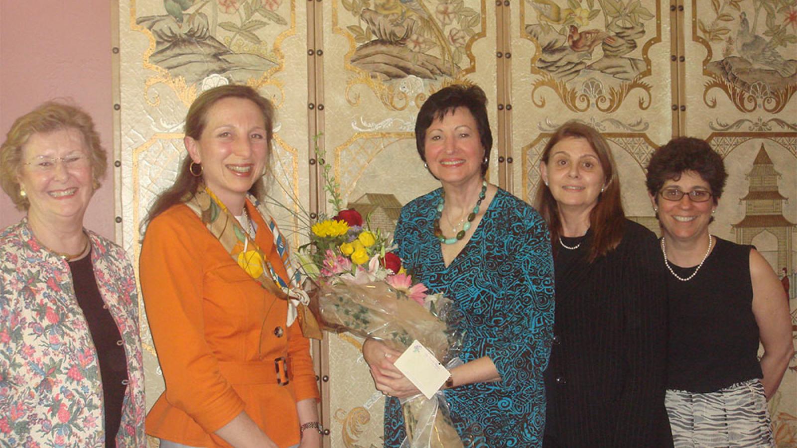 group of five women and one is holding a bouquet