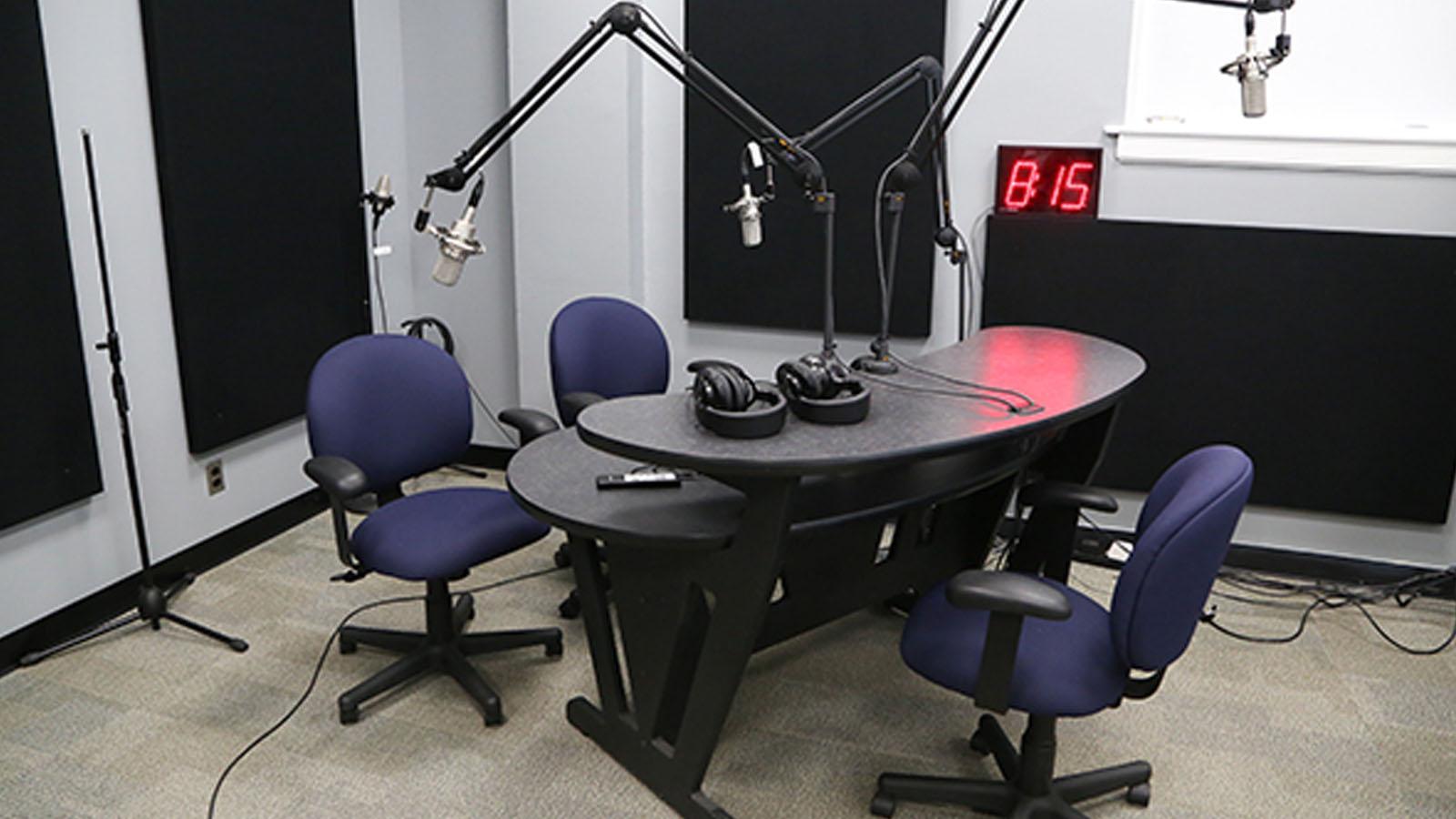 Inside the soundbooth with two microphones and a clock