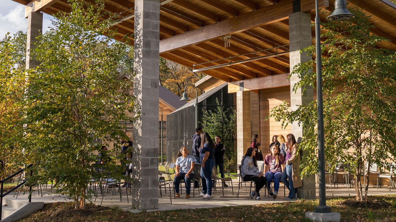 Outside classroom with a stanted roof and students underneath