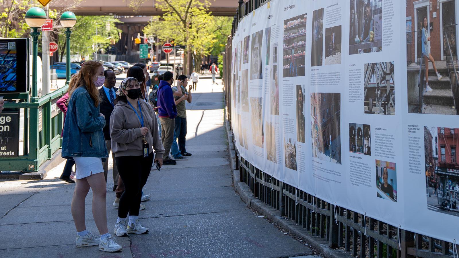 people on the street looking at a photo exhibit