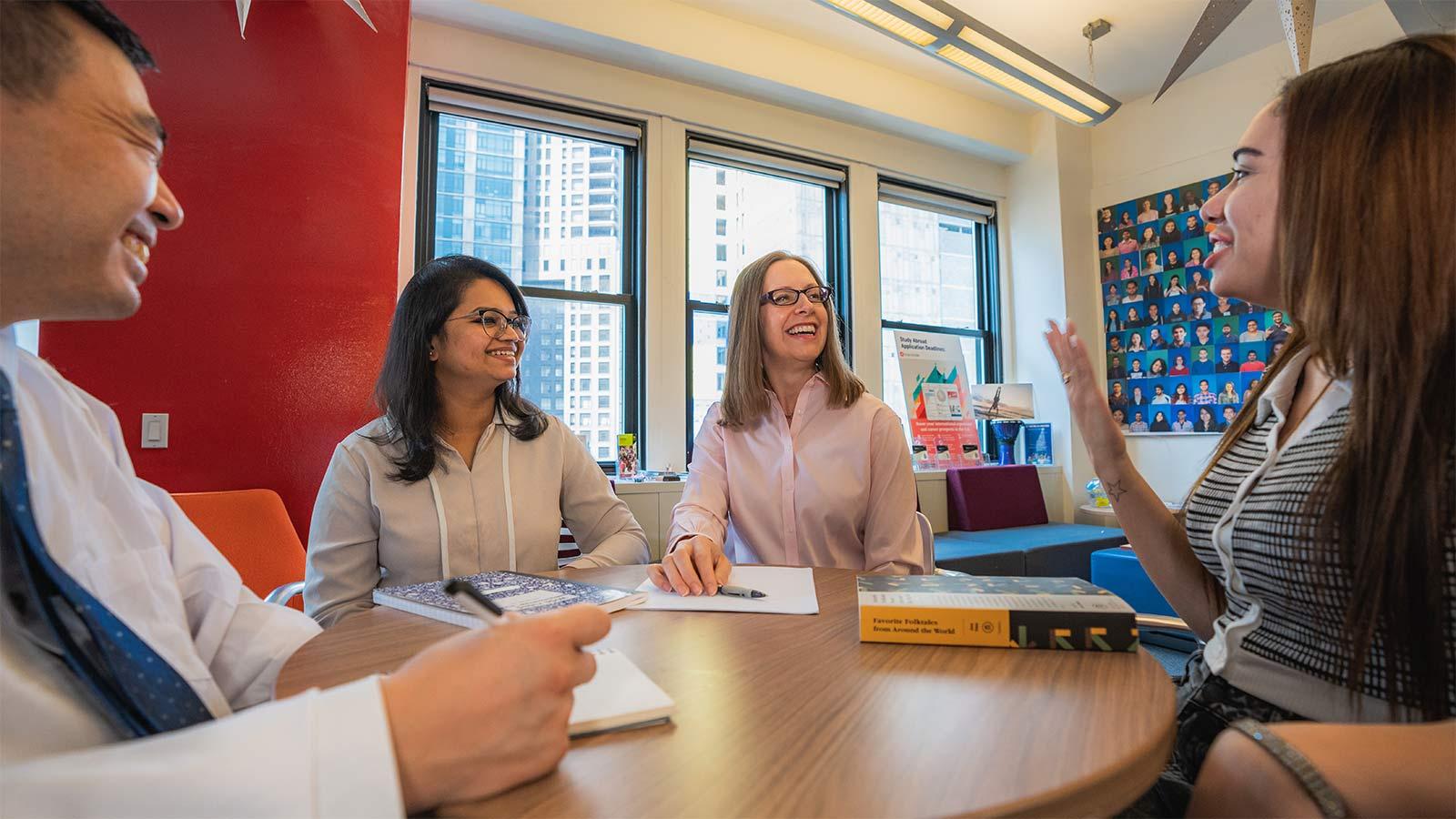 students and tutors sitting around a table talking