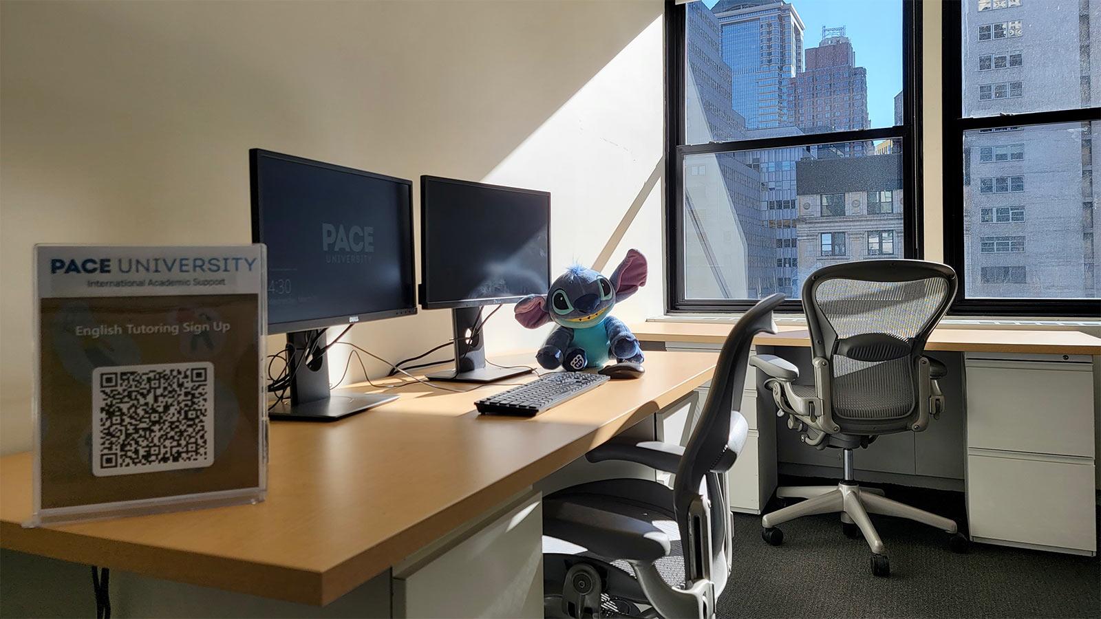 Desk with a laptop computer with two windows that overlook the New York City skyline.