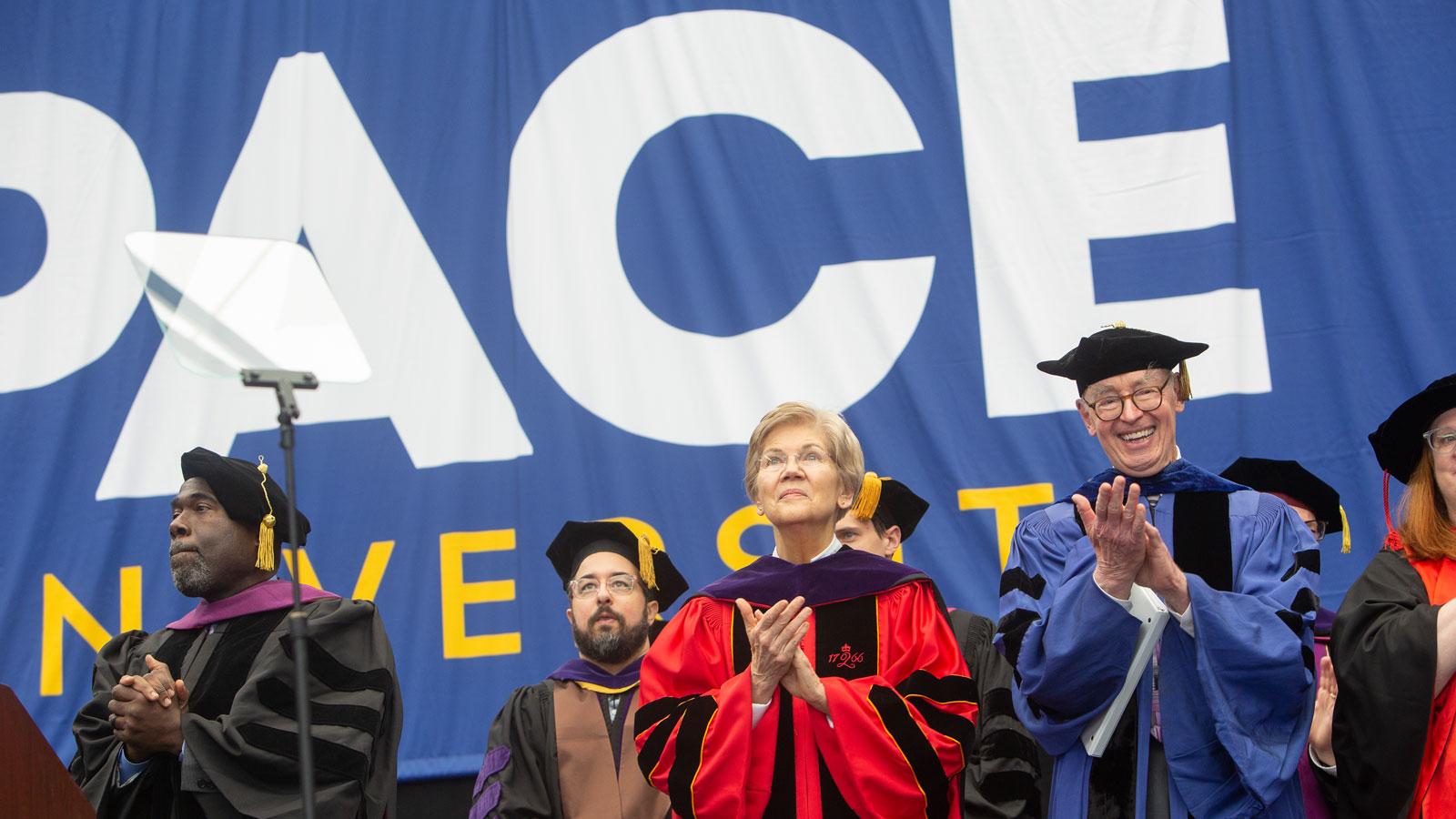 senator elizabeth warren and bruce h. mann on stage at graduation