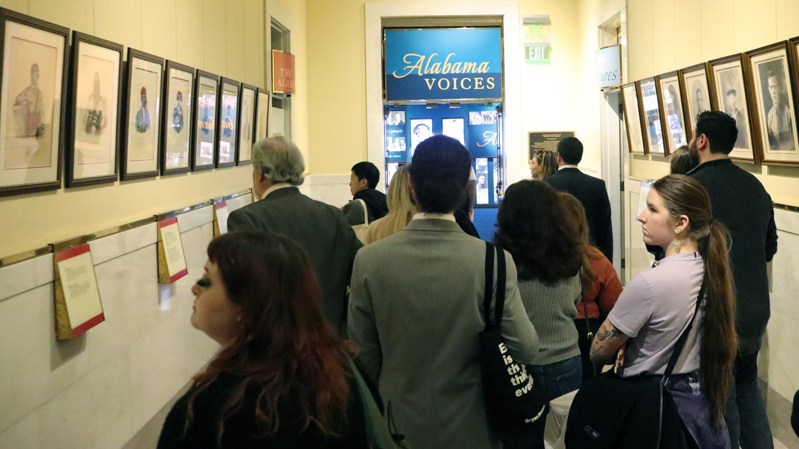 people in a hallway reading plaques