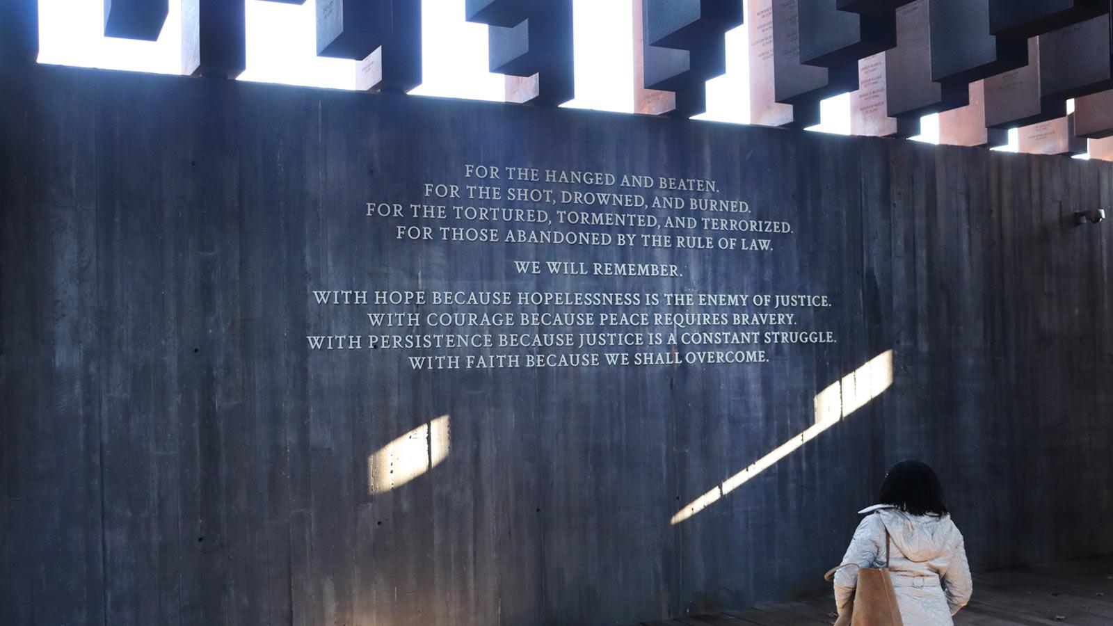 woman standing in front of a wall reading a quote