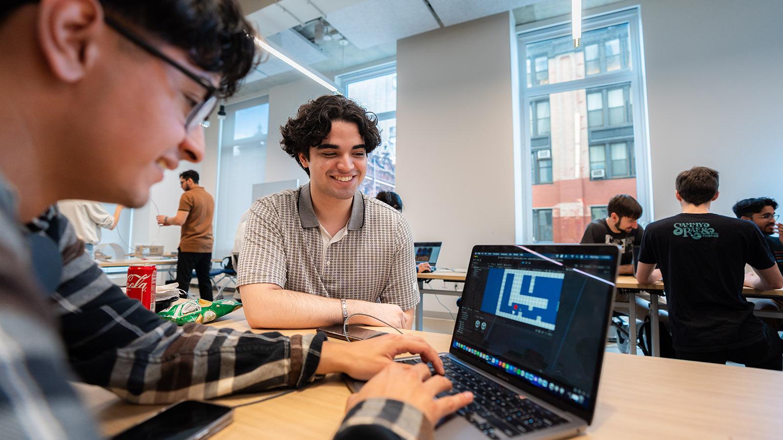 Two Pace students watch a video game animation on a laptop screen