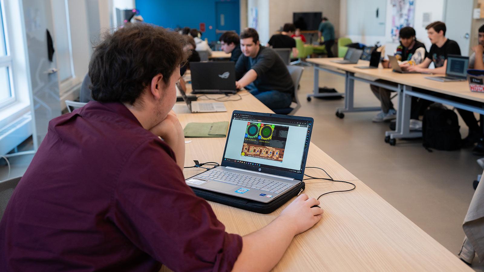 A Pace University student reviews a video game on a laptop